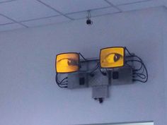 two yellow lights hanging from the ceiling in front of a white wall with an instagramt