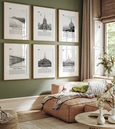 a living room with green walls and pictures on the wall above the couch, along with vases filled with flowers