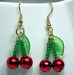 two cherries with green leaves and red pearls