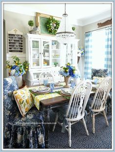 the dining room table is set with blue and white flowers in vases on it