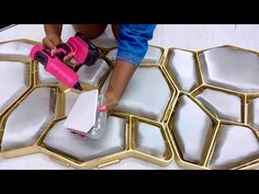 a person is painting some white and gold tiles on the floor with pink toys in front of them