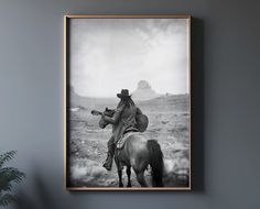 a black and white photo of a man on a horse with a guitar in his hand