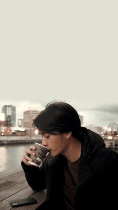 a man sitting on a bench drinking from a cup