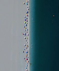 an aerial view of people on the beach with umbrellas in the sand and water