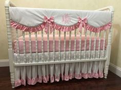 a white crib with pink ruffles and a monogrammed pillow