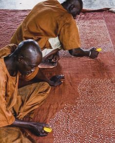 two men sitting on the ground working on something