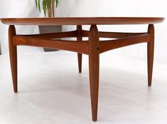 a wooden table sitting on top of a white floor next to a potted plant