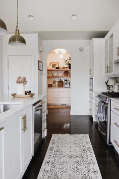 a kitchen with white cabinets and an area rug on the floor in front of it