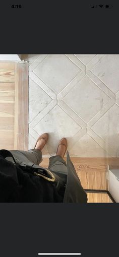 someone is standing on the floor with their feet propped up in front of a tile wall