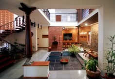 a living room filled with lots of furniture next to a stair case covered in plants