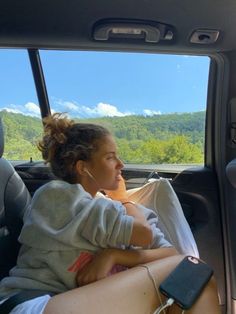 a woman sitting in the back seat of a car listening to music with headphones