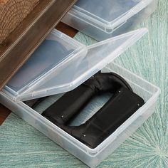 two plastic storage boxes with black handles on top of a wooden floor next to a rug