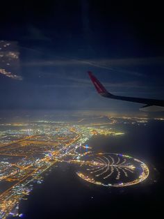 an aerial view of the city lights and water at night, taken from an airplane