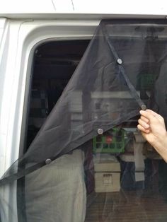 a person holding up a black tarp over the back of a white truck door