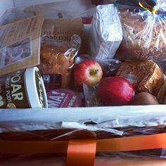 a basket filled with lots of food on top of a wooden table next to an orange ribbon