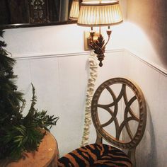 a zebra print chair next to a lamp on a wall with a mirror above it