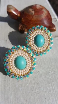 two blue and white beaded earrings sitting on top of a table next to a turtle