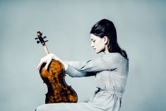 a woman sitting on the ground holding a violin