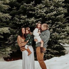 a family poses for a photo in front of some pine trees with snow on the ground