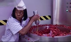 a woman in a white hat is pouring something into a metal container with meat on it