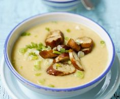 there is a bowl of soup with potatoes and celery on the table next to it