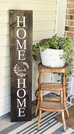 a wooden sign sitting on the side of a house next to a potted plant