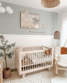 a baby's room with a crib, rocking chair and potted plant