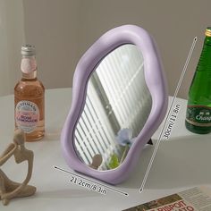 a purple mirror sitting on top of a table next to a bottle of booze