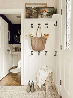 a basket hanging on the wall next to a white door with black handles and hooks