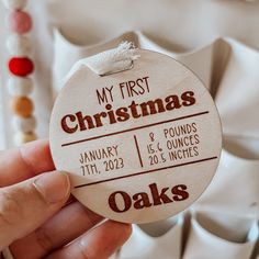 a person holding up a wooden ornament with the words my first christmas on it