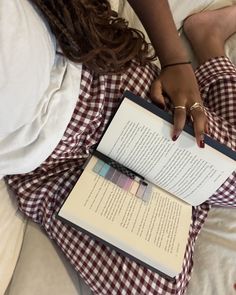 a woman laying in bed with an open book on top of her lap, reading