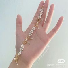 a person's hand wearing a gold bracelet with pearls and cross charms on it