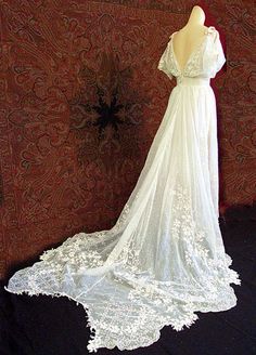 a white wedding dress on display in front of a red wall