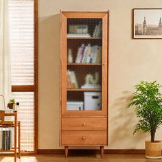 a tall wooden cabinet sitting next to a potted plant