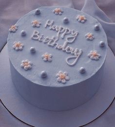 a blue birthday cake with white frosting and flowers