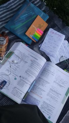 an open book sitting on top of a blanket next to a bottle of alcohol and other items