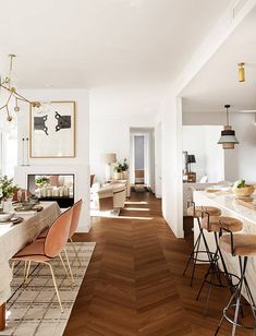 a dining room and kitchen area with wood flooring, white walls and wooden floors