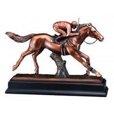 a bronze statue of a jockey riding a horse on a wooden base with a white background