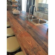 a kitchen counter with stools next to it and an island in the middle that is made out of wood