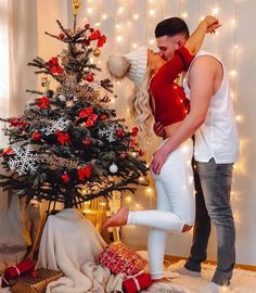 a man and woman standing in front of a christmas tree