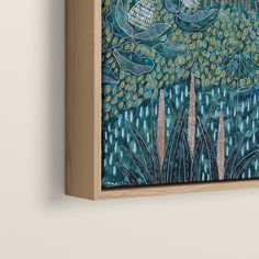 a painting hanging on the wall next to a wooden frame with an image of flowers and leaves