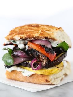 a close up of a sandwich with meat and veggies on it's bun