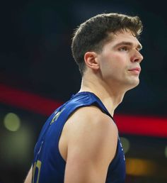 a male basketball player in a blue jersey looking up at the sky with his eyes closed