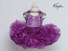 Make a sweet statement with the Sugar Kayne Little Girls Cupcake Pageant Dress! This darling dress features a choker neckline and a crystal beaded bodice that sparkles as she takes the stage. Short ruffled skirt and corset tie in back add playful, girly details. Choker neckline and crystal beaded bodice for stand-out style Short ruffled skirt creates a fun, bouncy silhouette Corset tie in back ensures a perfect fit Eye-catching design is perfect for pageants and special occasions With its cupcak Cupcake Pageant Dress, Short Ruffle Skirt, Baby Christening Outfit, Girls Corset, Girls Communion Dresses, Girl Cupcakes, Cupcake Dress, Girls Pageant Dresses, Christening Dress