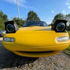 the front end of a yellow sports car with two speakers on it's hood