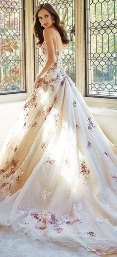 a woman in a wedding dress standing by a window