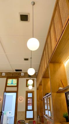 an empty room with wooden paneling and two round lights hanging from the ceiling above