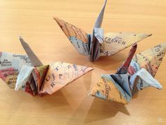 four origami cranes sitting on top of a wooden table