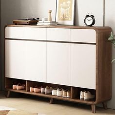 a white cabinet with shoes on it and a clock in the corner next to it