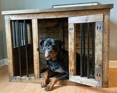 a dog sitting in a wooden crate with bars on the sides and his head sticking out